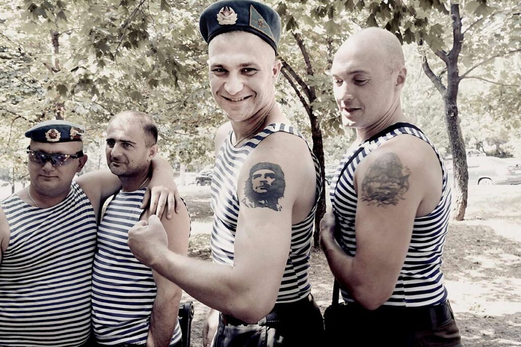 Two young soldiers showing their muscles and their tattoos during the day of the "paratroopers," an elite troop of the Russian army of which many inhabitants of Donbas belong. As young and old drink vodka, sing and have fun, fighting continues to rage a few kilometers away, Donetsk, Donetsk People's Republic, August 2017. Aude Osnowycz © All rights reserved.