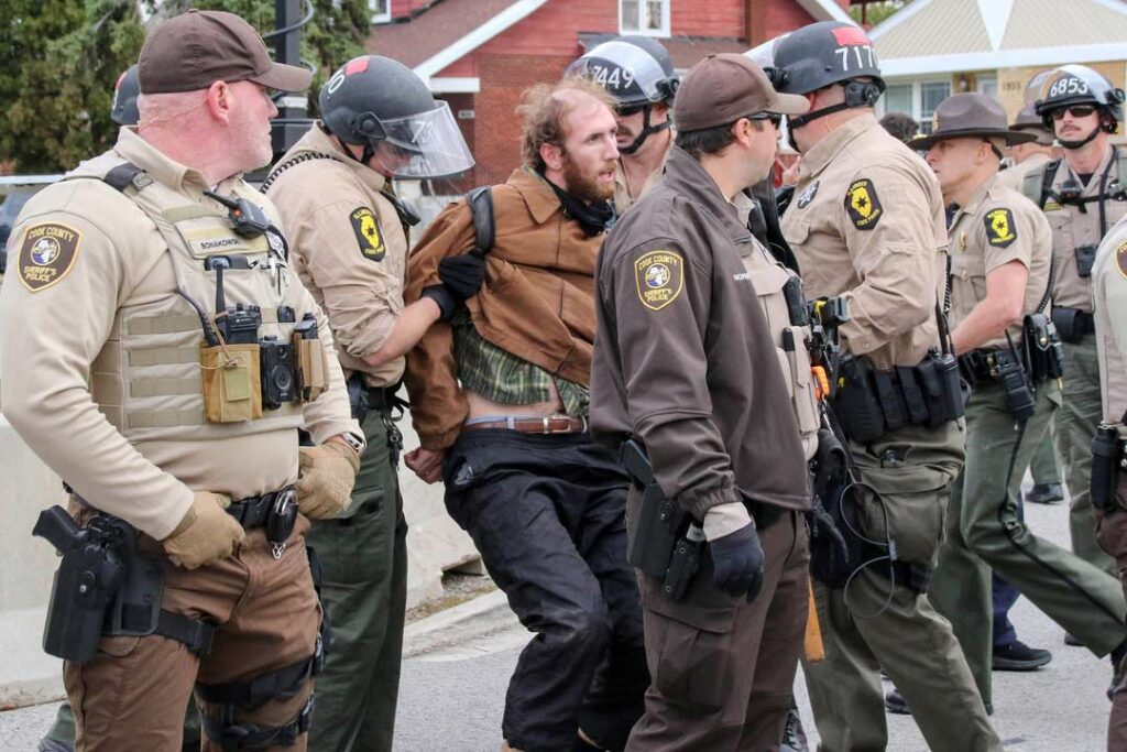  Broadview’s Stand #12
Sheriff's police detain a protester outside the ICE Detention Center on 25th Street and Harvard in Broadview, IL, USA. Broadview Mayor Katrina Thompson set hours for the protest from 9AM to 6PM and within designated protest zones behind concrete barriers.
Alexandra Buxbaum © All rights reserved.