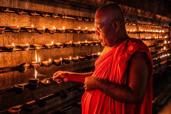 Keeper of the Flame Inside a Buddhist temple, a monk lights rows of oil lamps, a daily ritual of devotion and continuity. Through precise, repeated gestures, faith is practiced as lived experience, revealing how spirituality is sustained through ordinary acts within sacred spaces. Thibault Gerbaldi © All rights reserved